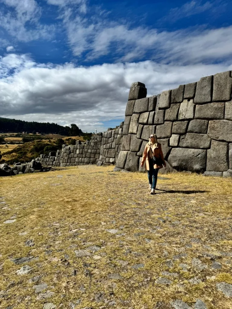 Viajante da Monde Travel caminhando junto às muralhas de pedra de Sacsayhuamán